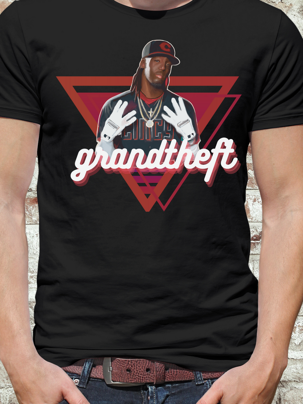 Black t-shirt featuring a stylized illustration of a baseball player with long hair and white gloves, layered gold chains, and a retro triangle backdrop, with the word "grandtheft" in bold cursive lettering.

