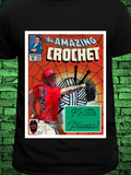 Blackt-shirt featuring a comic book-style design titled "The Amazing Crochet," showcasing a baseball player in a red jersey with the name "Crochet" and number 5, pitching in front of a yarn ball and crochet hooks with the phrase “Knitta Please!”