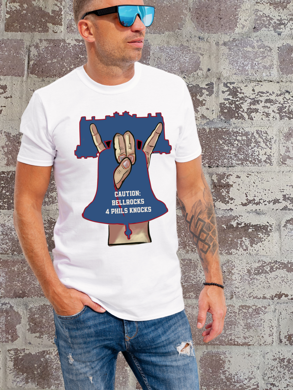 man in White t-shirt with a bold graphic of a hand gesture forming a bell shape inside a Liberty Bell outline, with text that reads “Caution: Bellrocks 4 Phils Knocks